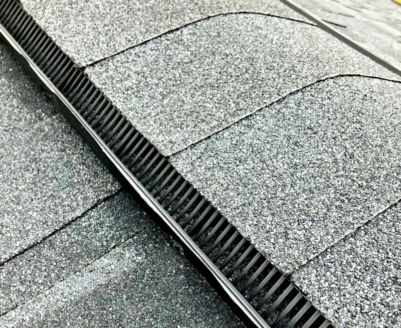 State Construction Ridge Vent Installation Close-up of an asphalt shingle roof with a newly installed ridge vent running along the roof peak for attic ventilation.